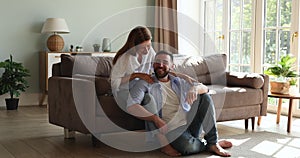 Laughing couple relax at home on weekend cuddle enjoy conversation