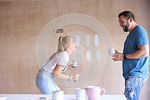 Laughing Couple Renovating Kitchen At Home Painting Tester Paint Colour Strips On Wall