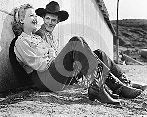 Laughing couple in western attire sitting on the ground