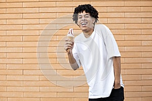 Laughing curly-haired African-American guy stained on nose with white ice cream, looking into the camera