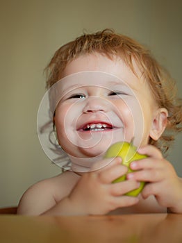 Laughing cute child eating apple fruit, portrait on blurred background. Enjoy eating moment. Healthy food and kid