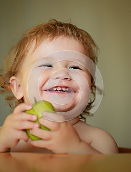 Laughing cute child eating apple fruit, portrait on blurred background. Enjoy eating moment. Healthy food and kid