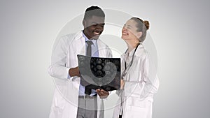 Laughing doctors studying X-ray on gradient background.