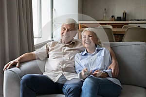 Laughing elderly spouses cuddle on couch watch tv movie comedy