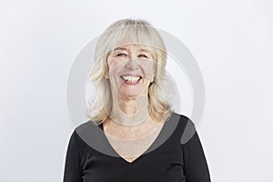 Laughing elderly woman. Beautiful lady in a black sweater. Positive and optimistic. White background. Close-up