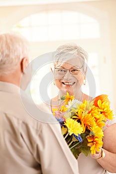 Laughing elderly woman getting bouquet