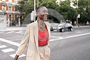 Laughing elegant young adult woman crossing the street in the city