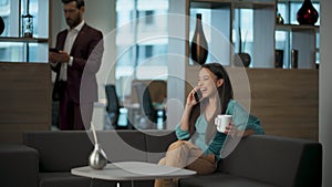 Laughing executive speaking mobile phone in panoramic office. Woman having fun