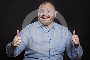 Laughing fat redhead man with a beard lives thumbs up. Black background