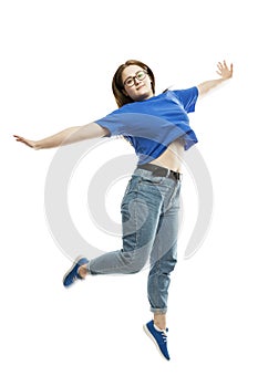 A laughing fat young girl in a blue tank top and jeans is emotionally jumping. Isolated on a white background. Full height.