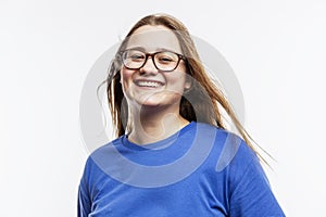 Laughing fat young girl with glasses in a blue t-shirt. Joy and happiness. White background. Close-up