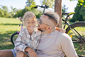 Laughing father and his daughter having fun together at the green park, relax and have fun together after cycling