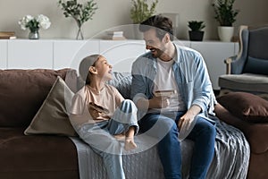 Laughing father and little daughter playing with wooden toy pistols