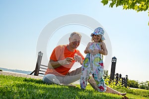 Laughing father and a small daughter are playing on a green mead