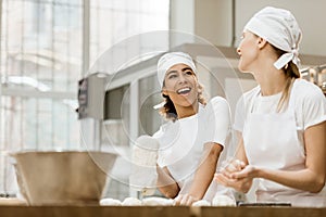 laughing female bakers kneading dough together