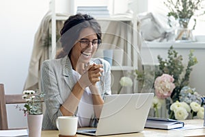 Laughing female enterpreneur decorator reading good news on laptop screen