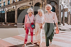 Laughing female friends in age are going across road