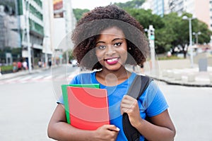 Laughing female student from Africa in blue shirt in city