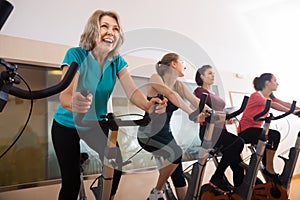 Laughing females of different age training on exercise bikes