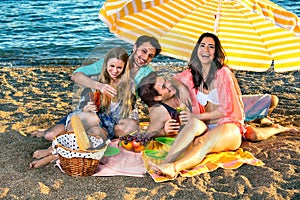 Laughing friends have picnic on the beach.