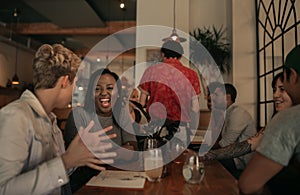 Laughing friends sitting at a bar table in the evening