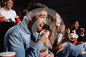 Laughing friends sitting in cinema watch film