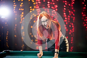 Laughing ginger woman playing billiard in nice architected club photo