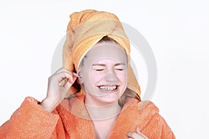 Laughing girl cleaning ears with cotton swab. Portrait teenage in towel on head