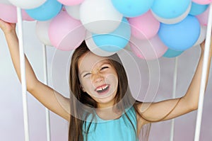 Laughing girl holds many colored balloons with her hands