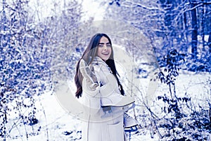 Laughing Girl Outdoors. Model wearing stylish sweater and gloves. Portrait of a young woman in snow trying to warm