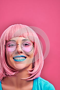 Laughing girl with pink hair, blue lips and sunglasses. Stylish hair color trend