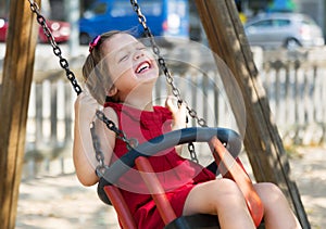 Laughing girl in red dres on swing