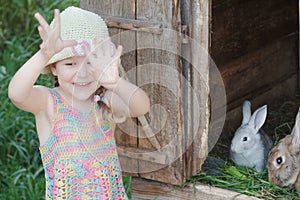 Laughing girl showing hands in front of farm hutch with domestic rabbits