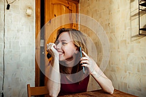 A laughing girl sits at the chair with a phone in her hands waiting for a call