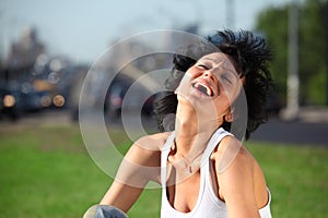 Laughing girl sits on lawn at road in city