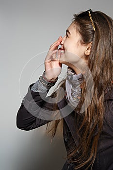 Laughing girl standing in profile and covering mouth with hand