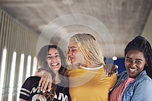 Laughing girlfriends walking together in the city at night