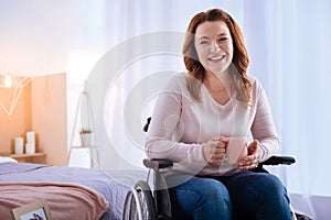 Laughing gleeful disabled woman holding a cup