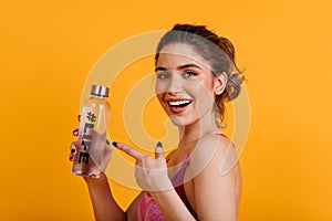 Laughing good-looking woman posing after training. Indoor shot of adorable sporty girl drinking water