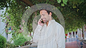 Laughing guy calling mobile phone at cozy alley closeup. Man talking smartphone