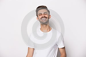 Laughing guy wearing white t-shirt posing on studio background