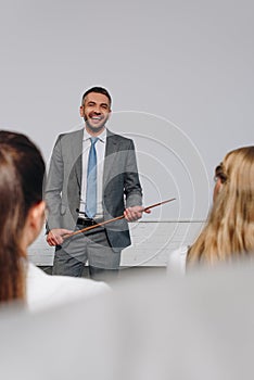 laughing handsome business coach holding pointer stick during training