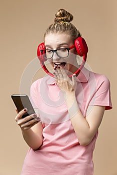 Laughing Happy Caucasian Girl In Casual Clothing Posing With Wireless Headphones And Cellphone While Laughing Against Beige