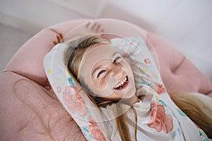 Laughing happy girl lying on a pink pillow