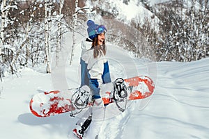 Laughing happy girl with a snowboard and background of mountains and snowy trees