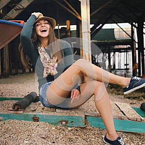 Laughing hipster girl portrait under the old pier on a sea beach.