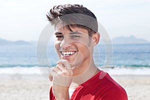 Laughing hispanic guy at beach looking at camera