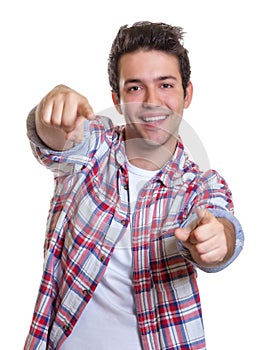 Laughing hispanic guy pointing with both hands at camera