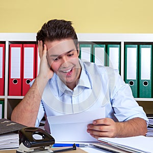 Laughing hispanic guy reading a message at office