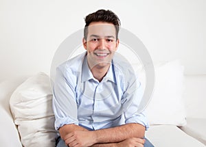Laughing hispanic guy on a sofa